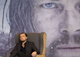 Léonardo-DiCaprio-assis sur un fauteuil et deriière l'affiche de son film le Revenant- film-Part-2-Atlaneastro